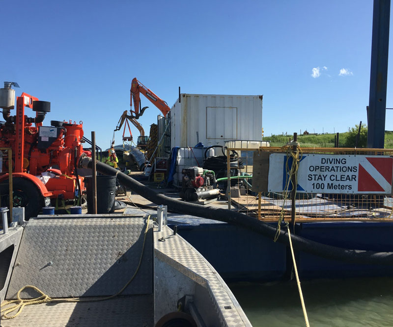 Barge assembly used to aid with liner installation getting loaded before being towed out to open water.